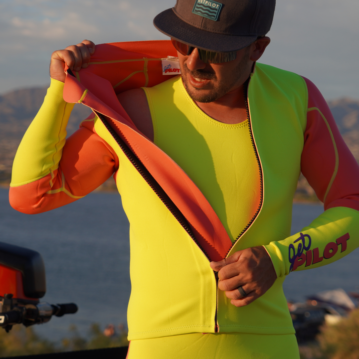 Man wearing a bright yellow and orange wetsuit with a mountainous background #color_neon-pink