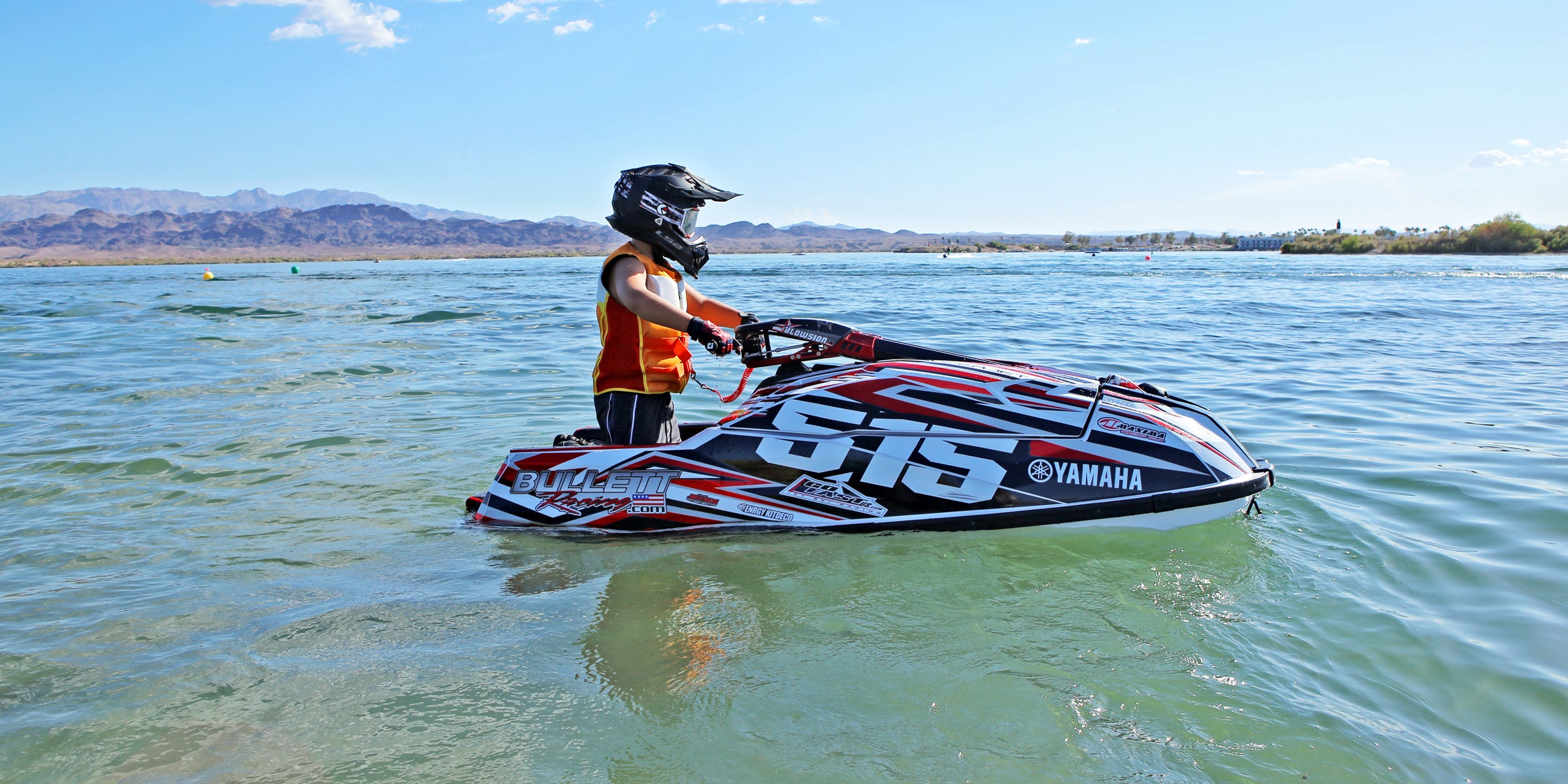 A young rider on the jet ski wearing our Youth Vintage Class Neoprene CGA Vest in the color Orange/White.