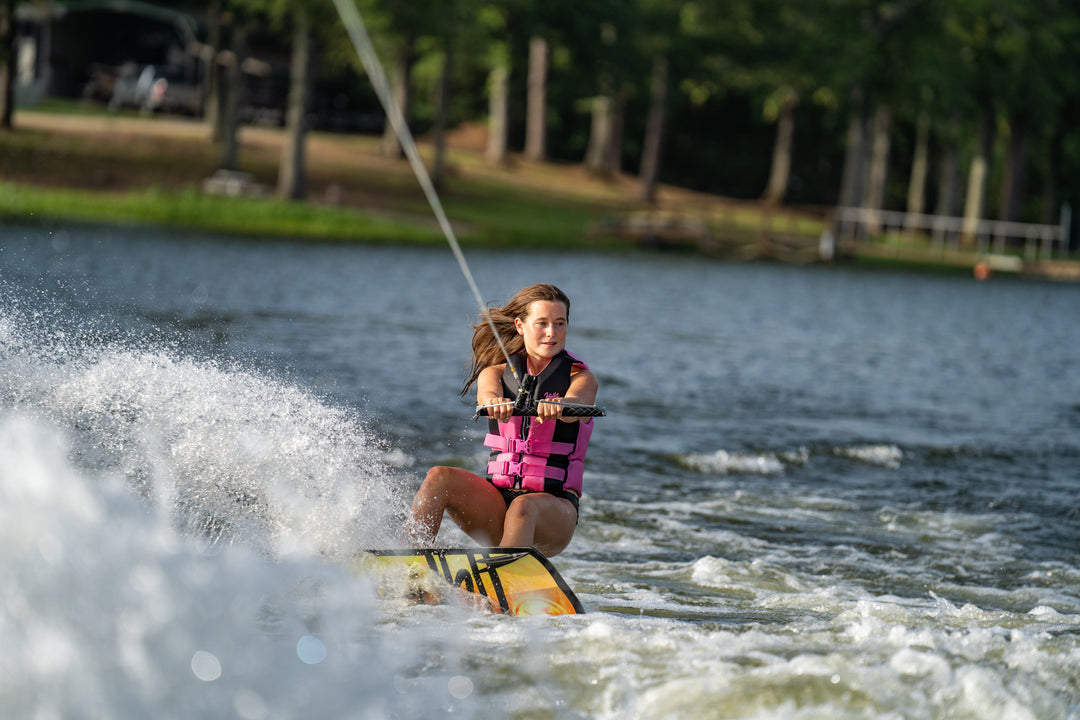 Person wakeboarding on a lake with trees in the background #color_pink