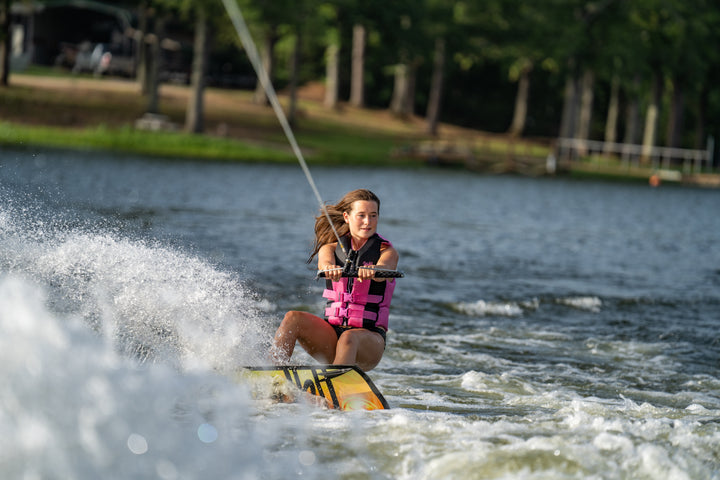 Person wakeboarding on a lake with trees in the background #color_pink