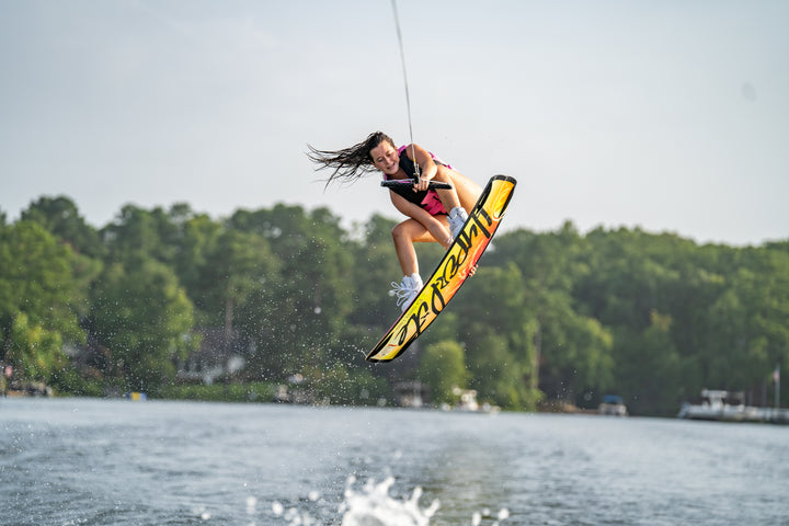 Person wakeboarding on a lake with trees in the background #color_pink