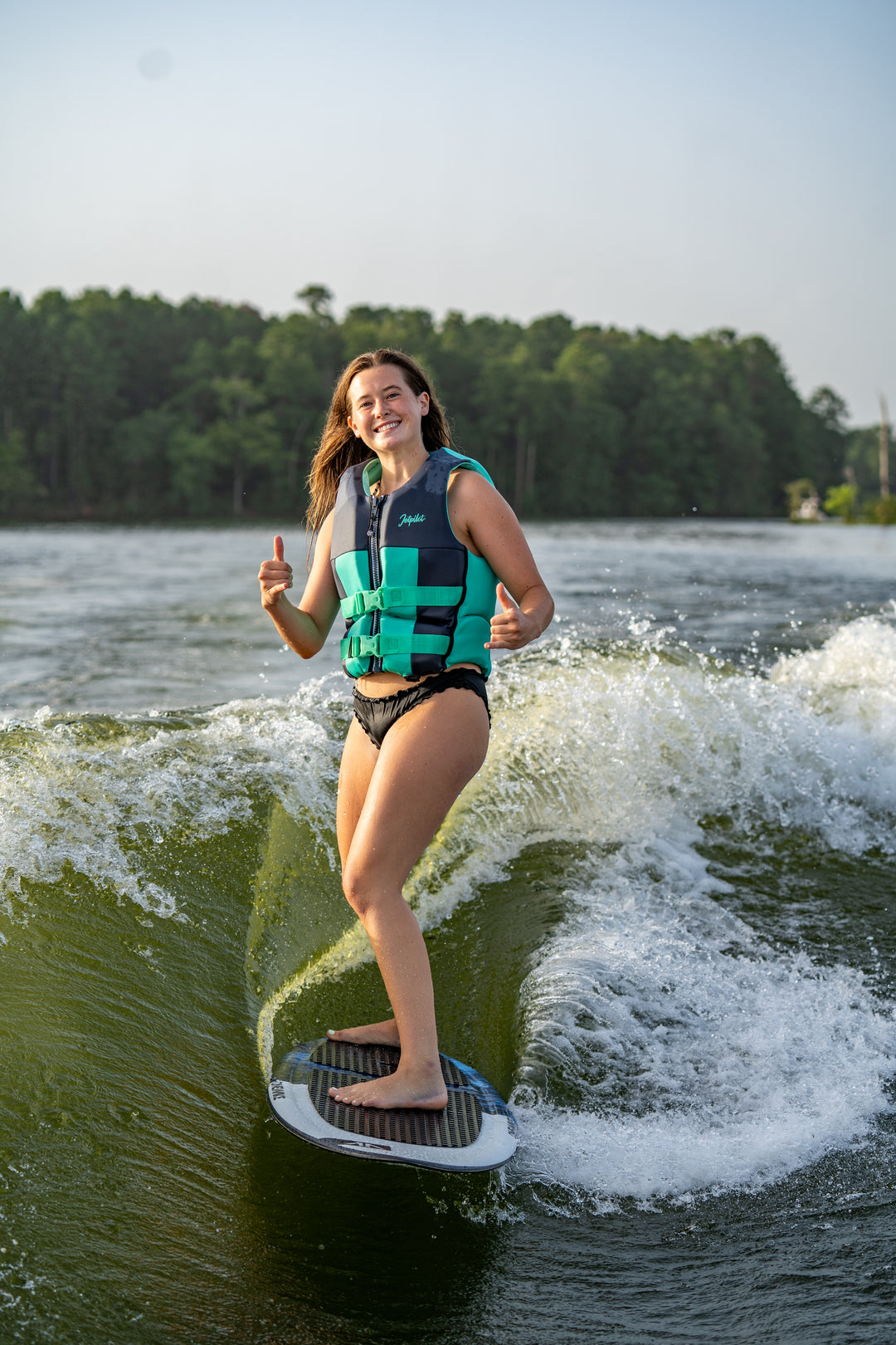 Person wakeboarding on a lake with trees in the background #color_teal