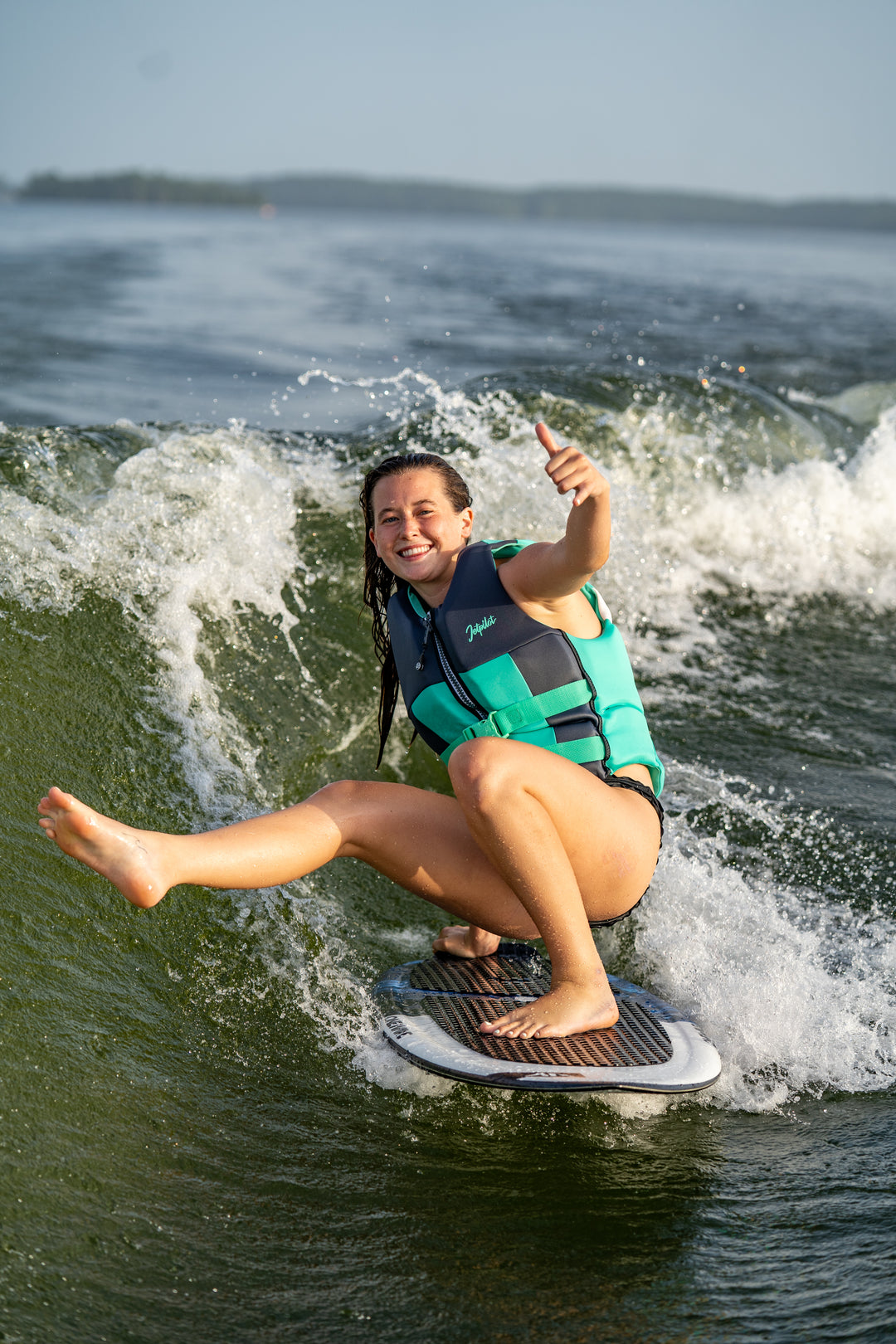 Person on a wake surf giving a thumbs-up in the water #color_teal