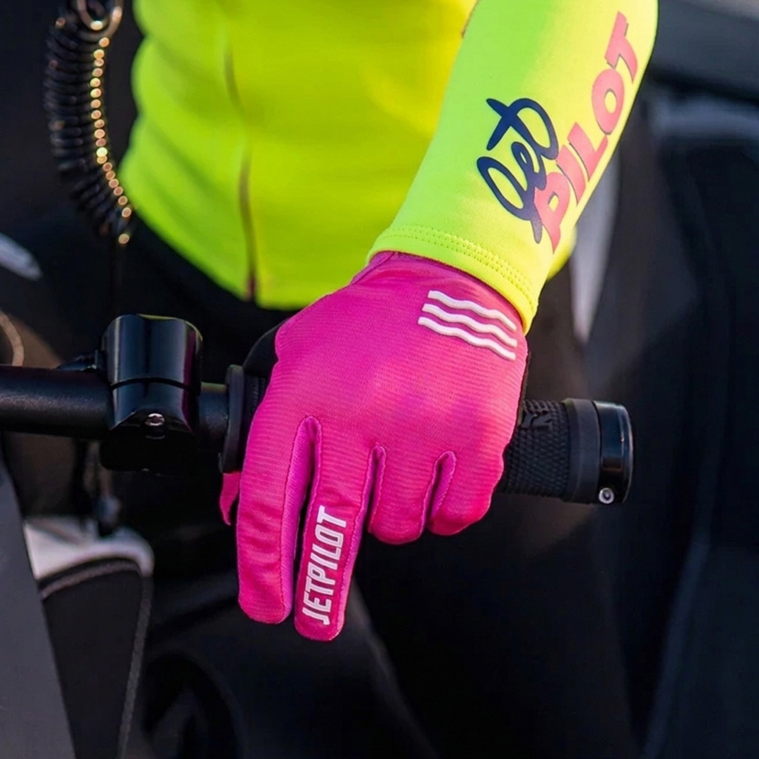 Person wearing a bright pink glove with 'JetPilot' branding on a bike handlebar. #color_pink