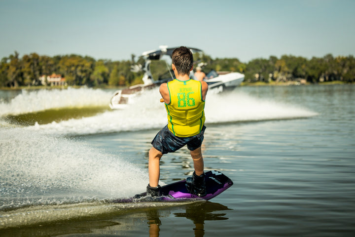 Person water skiing on a lake with a boat in the background. #color_yelbrz