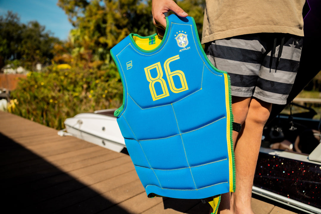 Person holding a blue life vest with yellow numbers outdoors. #color_yelbrz