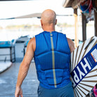 Man wearing a blue life jacket on a dock. #color_navy