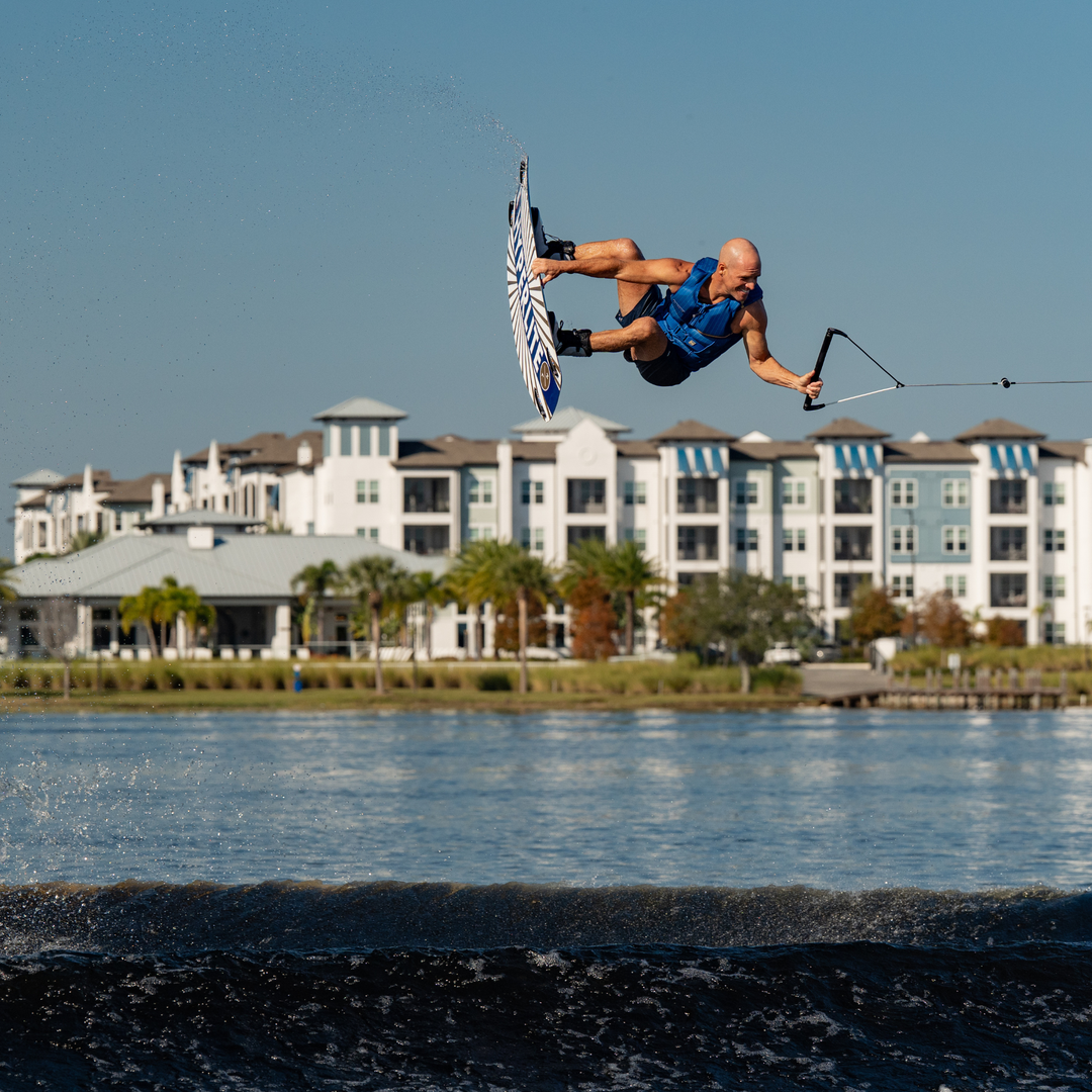 Person wakeboarding on water with buildings in the background. #color_navy