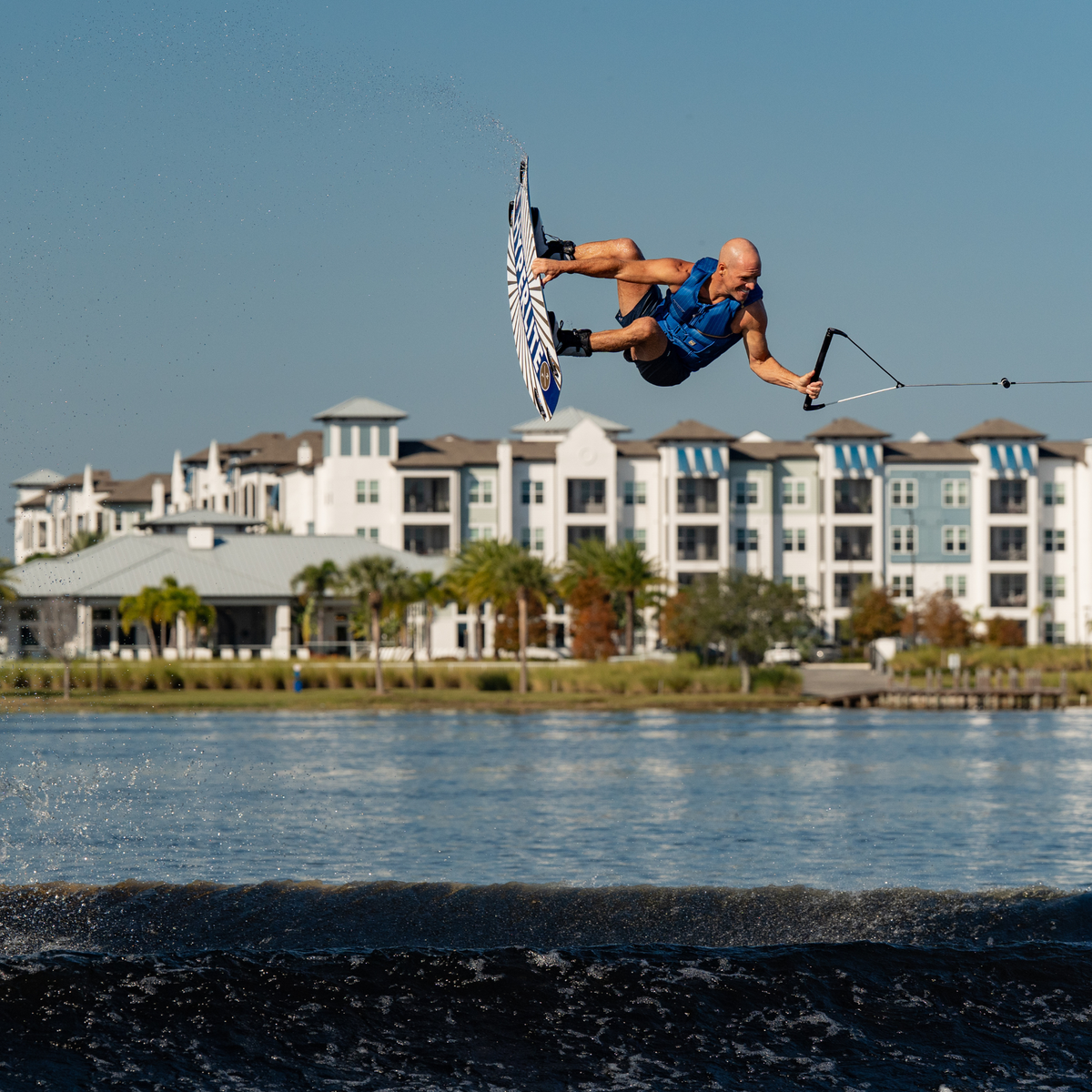 Person wakeboarding on water with buildings in the background. #color_navy
