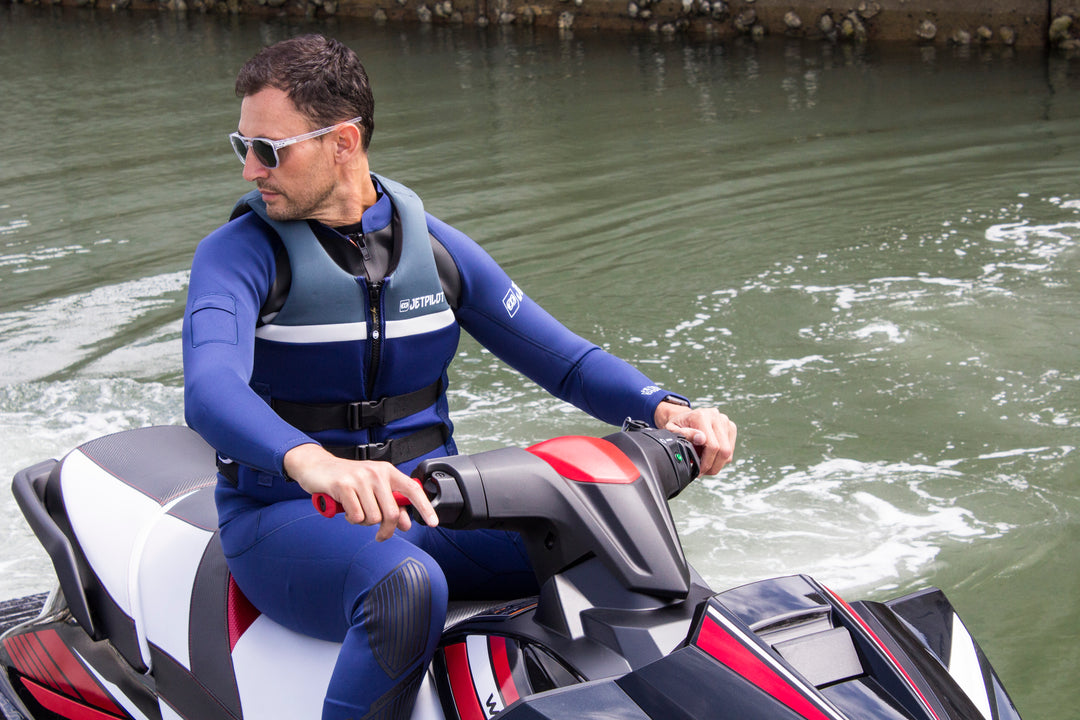 Picture of a man riding on a jet ski wearing the Blue colorway Jetpilot L.R.E. vest and john jacket combo.
