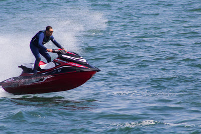 Picture of a man riding a jet ski wearing the Jetpilot L.R.E. vest and john jacket combo.